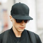 Man wearing sunglasses and baseball cap to deal with light sensitivity